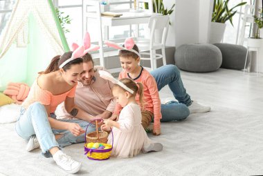 Evde paskalya yumurtaları ve tavşan kulakları olan mutlu bir aile.