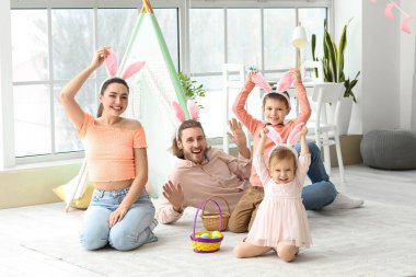 Evde paskalya yumurtaları ve tavşan kulakları olan mutlu bir aile.