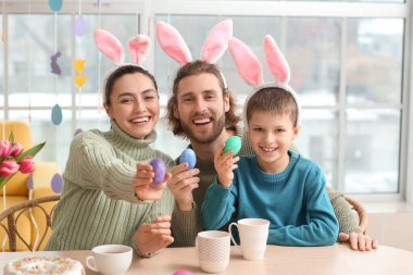 Mutlu ebeveynler ve Paskalya yumurtaları masada oturan küçük oğulları.