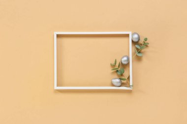 Çerçeveli güzel kompozisyon, Paskalya yumurtaları ve renk arkaplanındaki okaliptüs dalları