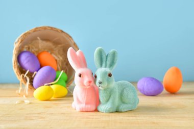 Renkli yumurtaları olan Paskalya tavşanları ve sepeti.