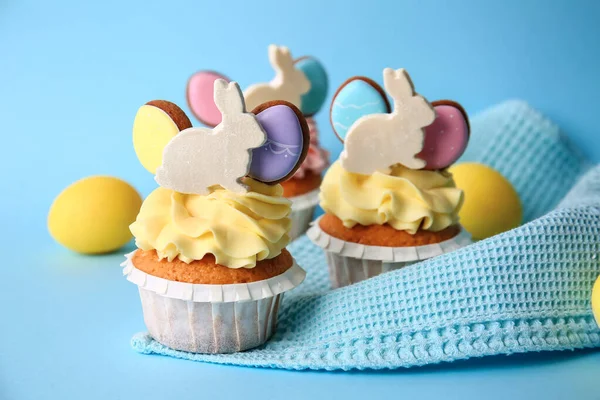 Lezzetli paskalya çörekleri ve yumurtalar mavi arka planda, yakın plan.