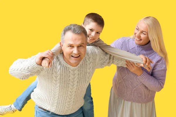 小さな男の子とともに彼の祖父母で暖かいセーターで楽しいです上の黄色の背景 — ストック写真
