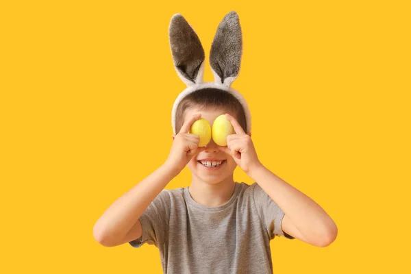 面白いです男の子とともにウサギの耳とイースターエッグ上の黄色の背景 — ストック写真
