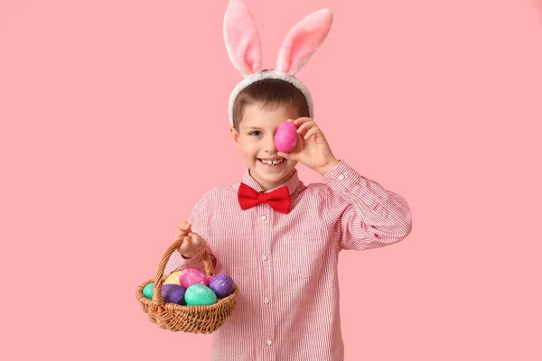 可爱的小男孩 长着小兔子耳朵 戴着粉色背景的复活节篮子 — 图库照片