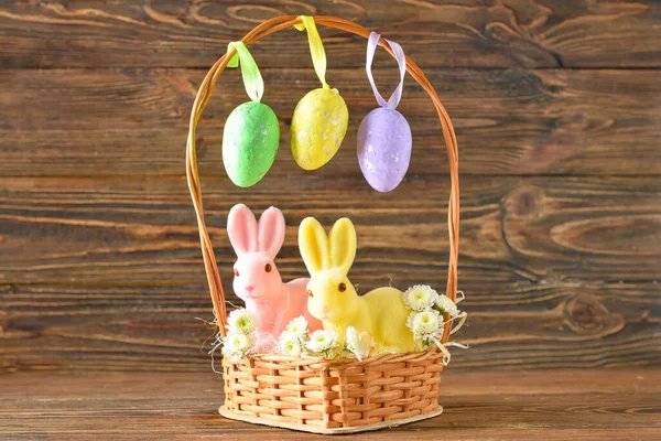 篮子里有可爱的复活节兔子和木制背景的鸡蛋 — 图库照片