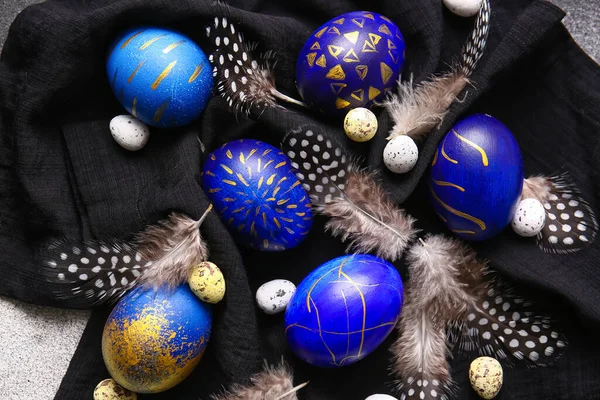 Paskalya yumurtaları ve tüyleri koyu renk kumaş arka planda.