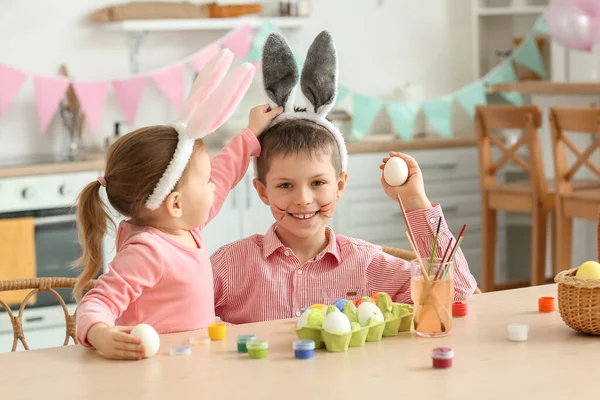 可愛いです女の子でウサギの耳とともに彼女の兄Paitingイースターエッグホーム — ストック写真