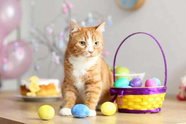 可爱的红猫 带着复活节彩蛋和篮子坐在桌子上 — 图库照片