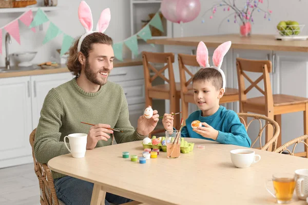 Mały Chłopiec Ojcem Króliczych Uszach Maluje Wielkanocne Jajka Domu — Zdjęcie stockowe