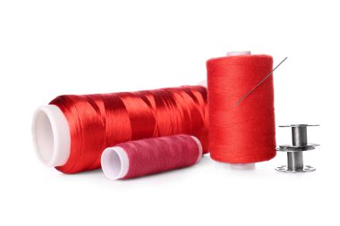 Beyaz arkaplanda kırmızı iplik makaraları ve iğne