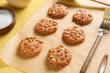 Sarı arka planda lezzetli fıstıklı kurabiyeler olan parşömen kağıdı.