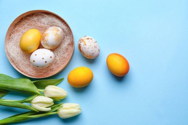 Renkli arkaplanda güzel Paskalya yumurtaları ve lale çiçekleri olan kompozisyon