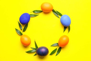 Güzel Paskalya yumurtalarından ve sarı arka planda bitki yapraklarından yapılmış çerçeve.