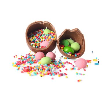 Kırık çikolata Paskalya yumurtası ve beyaz arka planda farklı şekerler.