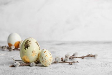 Beautiful Easter eggs and pussy willow branches on light background