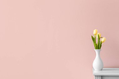 Renk duvarının yanındaki çekmecelerde laleler olan vazolar.