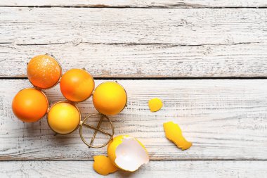 Boyanmış Paskalya yumurtaları ve beyaz ahşap arka planda yumurta kabuğu olan tutucu