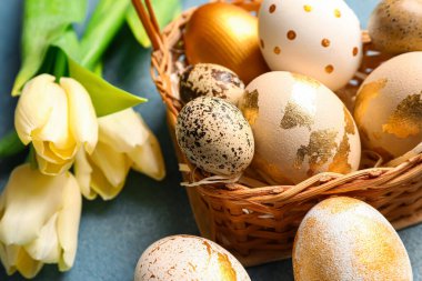 Renkli Paskalya yumurtaları ve lale çiçekleriyle dolu hasır sepet.