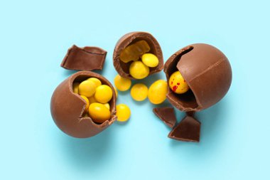 Kırık çikolatalı Paskalya yumurtaları ve mavi arka planda şekerler.