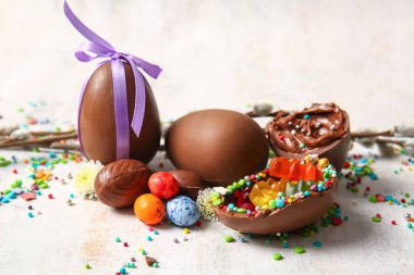 Çikolatalı Paskalya yumurtaları farklı şekerler ve hafif arka planda serpiştirilmiş şekerler, yakın plan.