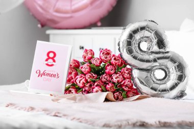 Bir buket lale, şekil 8 şeklinde balon ve yatakta mutlu kadınlar günü yazılı tebrik kartı.