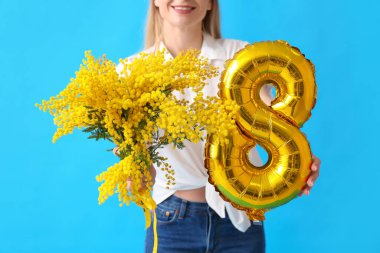 Şekil 8 şeklinde balonu ve mavi arka planda mimoza çiçekleri olan güzel bir kadın. Uluslararası Kadınlar Günü