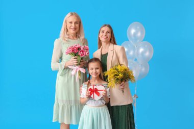Genç kadın, küçük kızı ve annesi mavi arka planda hediyeler.