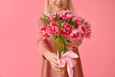 Pembe arka planda bir buket lale olan olgun bir kadın. Uluslararası Kadınlar Günü