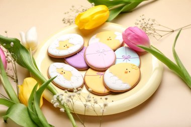 Yaratıcı Paskalya kurabiyeleri ve bej arka planda çiçekler olan tabak, yakın plan.