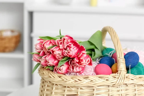 Paskalya yumurtaları ve çiçeklerle dolu bir sepet.