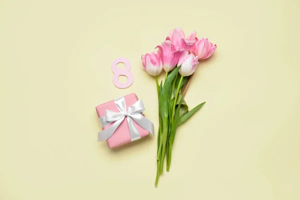 Composition with gift for International Women's Day and bouquet of beautiful tulips on color background