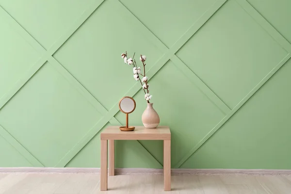 壁の近くの木製のテーブルの上に綿の花と鏡の花瓶 — ストック写真