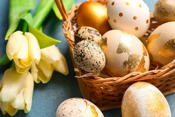 Renkli Paskalya yumurtaları ve lale çiçekleriyle dolu hasır sepet.