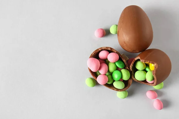 壊れたチョコレートイースターの卵と異なるキャンディーの光の背景 — ストック写真