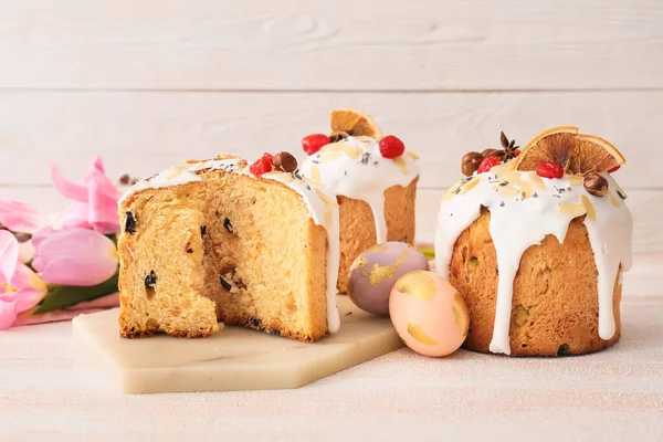 Lezzetli paskalya pastaları ve beyaz ahşap arka planda yumurtalar.