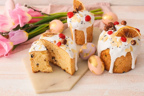 Lezzetli paskalya pastaları ve beyaz ahşap arka planda yumurtalar.