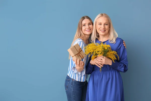 Young Woman Her Mother Gift Flowers Blue Background — Stock Photo, Image