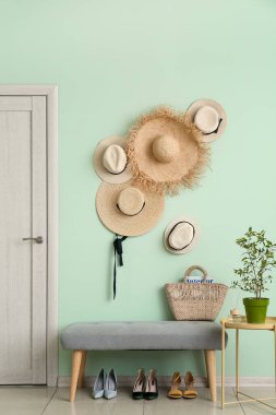 Hasır şapkalı, banklı, ayakkabılı ve çiçekli koridorun içi.