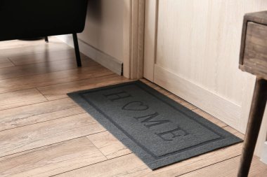 Koridordaki ahşap kapının yanındaki modern paspas. Yakın plan.