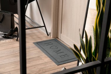 Koridordaki ahşap kapının yanındaki modern paspas.