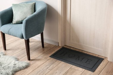 Modern salonda açık ahşap kapının yanındaki siyah paspas.