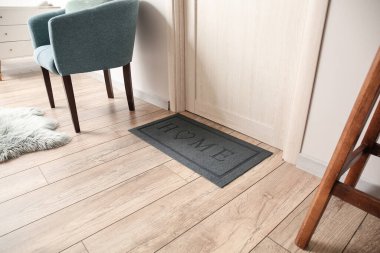 Modern salonda açık ahşap kapının yanındaki siyah paspas.