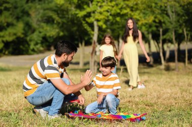 Uçurtmalı küçük çocuk dışarıda babasına beşlik çakıyor.