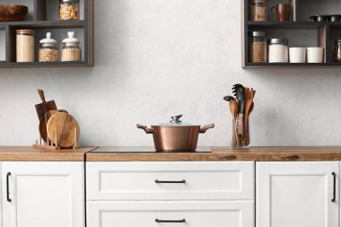 Copper cooking pot on stove near light wall in kitchen clipart