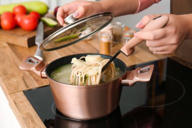 Kadın evde makarna ile lezzetli çorba pişiriyor, yakın plan.