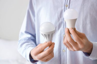 Yatak odasında ampulleri tutan adam, yakın plan.