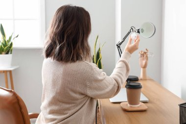 İş yerinde ampulü siyah lambayla değiştiren kadın.