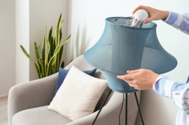 Evdeki standart lambada ampulü değiştiren kadın, yakın plan.