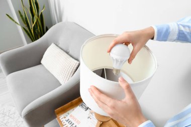 Evde ampulü değiştiren kadın, yakın plan.